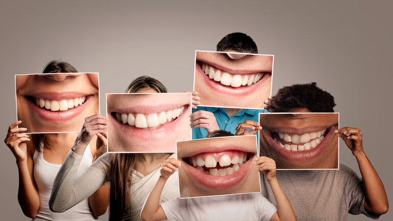 Gruppe glücklicher Menschen, die ein Bild eines lächelnden Mundes vor grauem Hintergrund halten